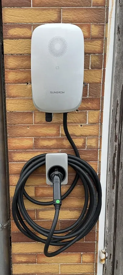 Installierte Wallbox, industrielle Kabeltrassenverlegung und Einsatzfahrzeug vor Neubau