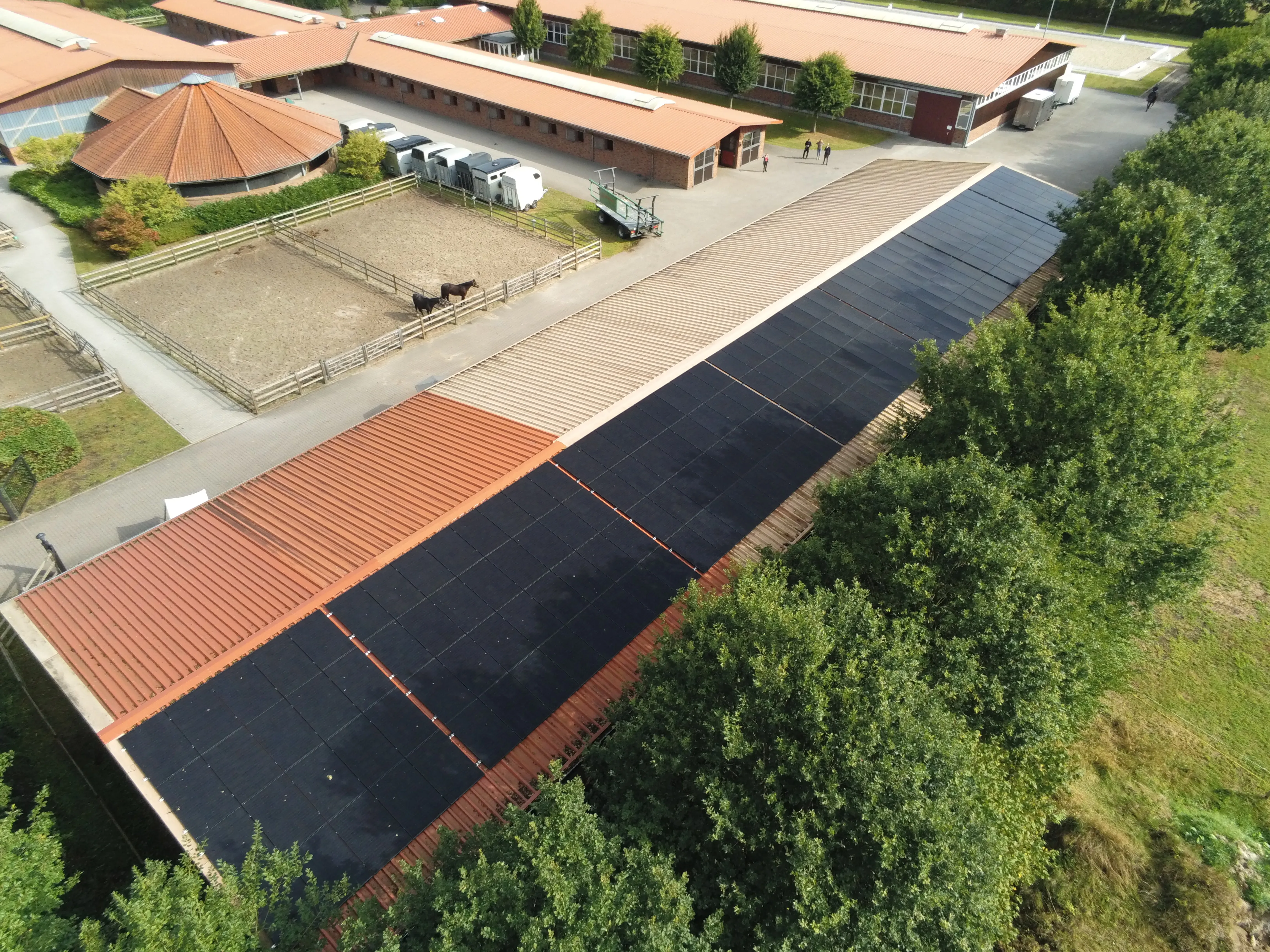 Drohnenaufnahme einer großflächigen Photovoltaikanlage auf dem Dach einer Reitanlage